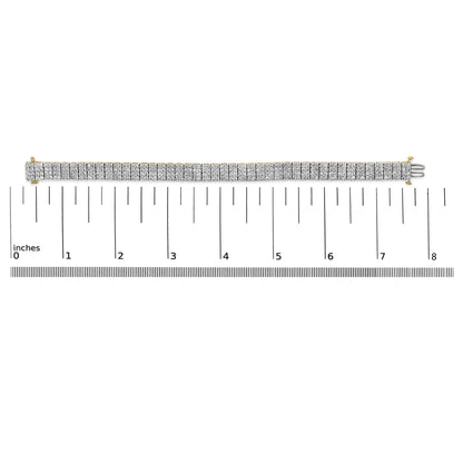Yellow metal bracelet with rows of white round gemstones in shared prong setting, displayed flat on a ruler scale, shot from above.
