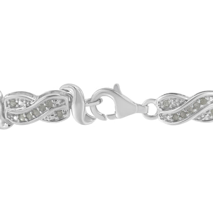 Close-up front angle of a white metal bracelet with a lobster clasp and linked segments featuring a waved design set with round white gemstones in pave setting.
