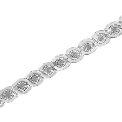 Close-up diagonal shot of a white metal bracelet featuring round white gemstones set in a miracle setting.