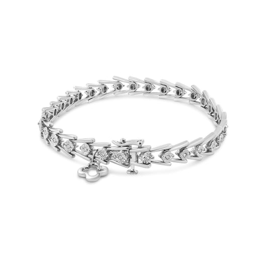 White metal bracelet with round white gemstones in a miracle setting, shown at an angled top view with a small dangling clover-shaped charm.