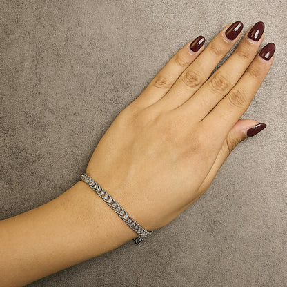 White bracelet with round white gemstones in a miracle setting, shown on a model's wrist from above.