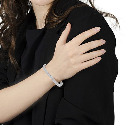 White metal bracelet with round white gemstones in miracle setting, worn on model's wrist, angled side view.