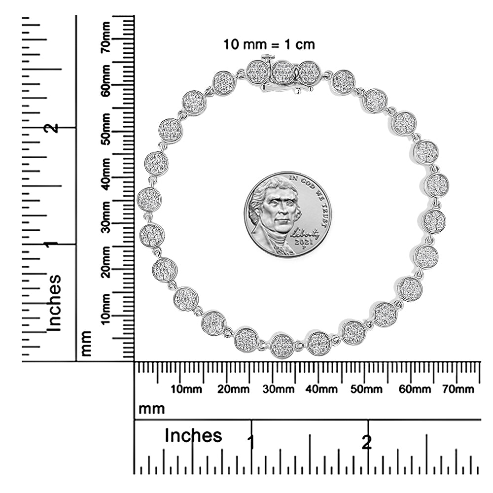 Top view of a white metal bracelet with round white gemstones in prong settings, displayed on a ruler and scale for size reference.