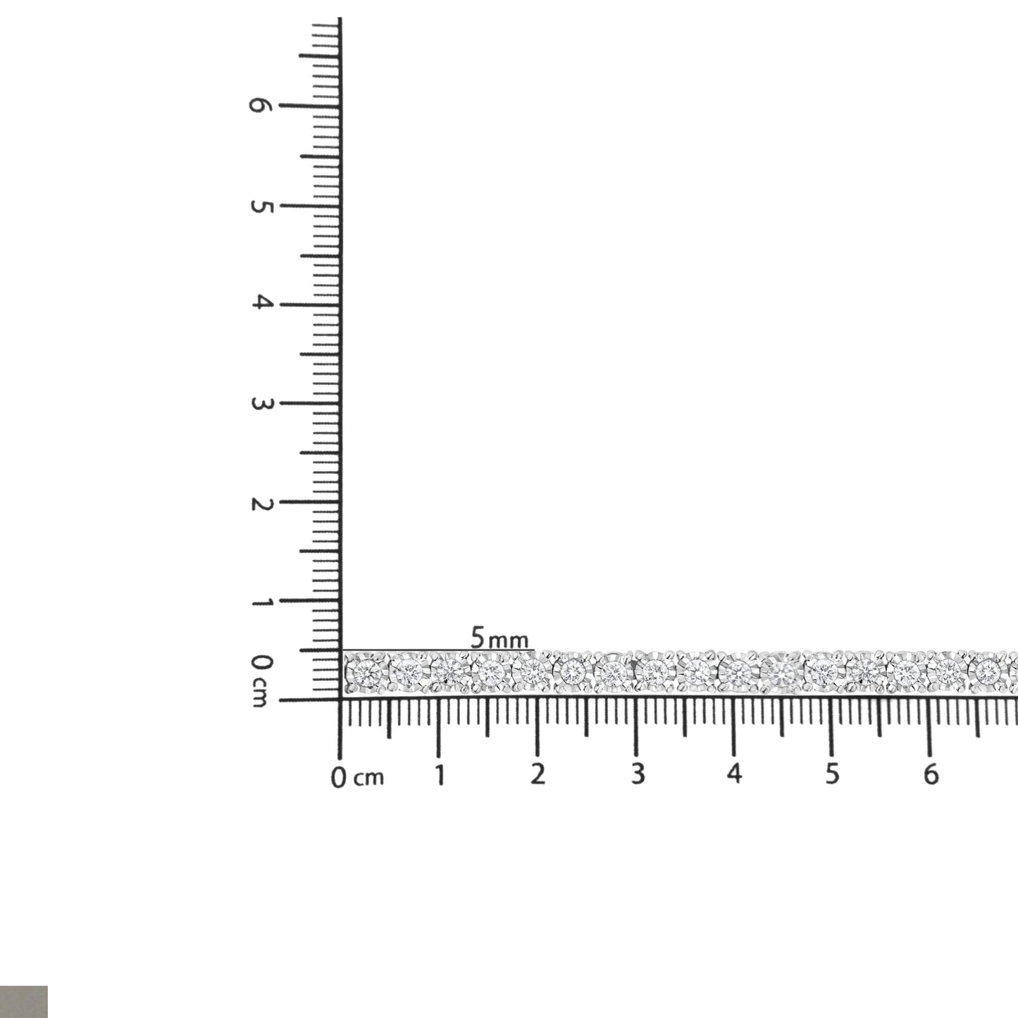 White metal bracelet with round white gemstones in miracle setting, laid flat on a ruler for size reference, top-down view.