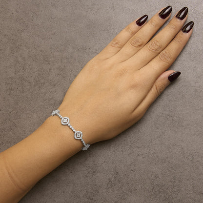 White metal bracelet with alternating square-shaped clusters and round gemstones, worn on a model's wrist, top-down angled shot.