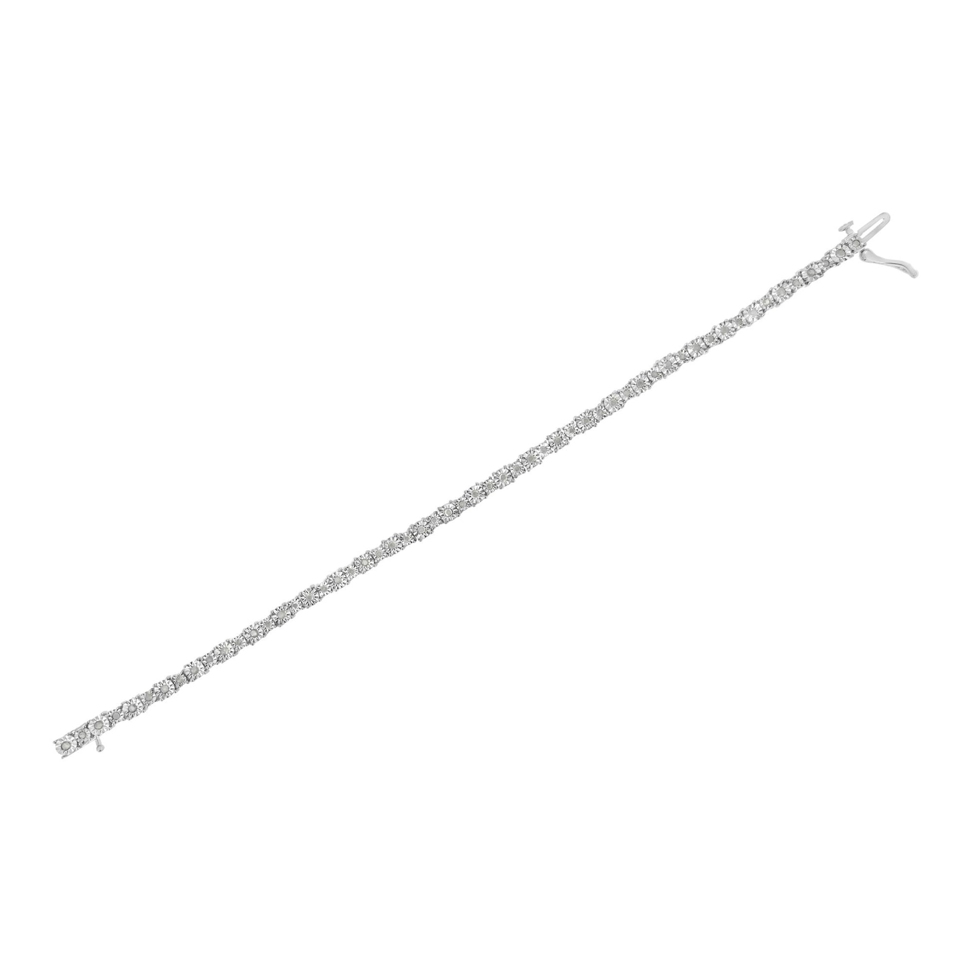 Diagonal top-down view of a white metal bracelet featuring a row of round white gemstones in a miracle setting.