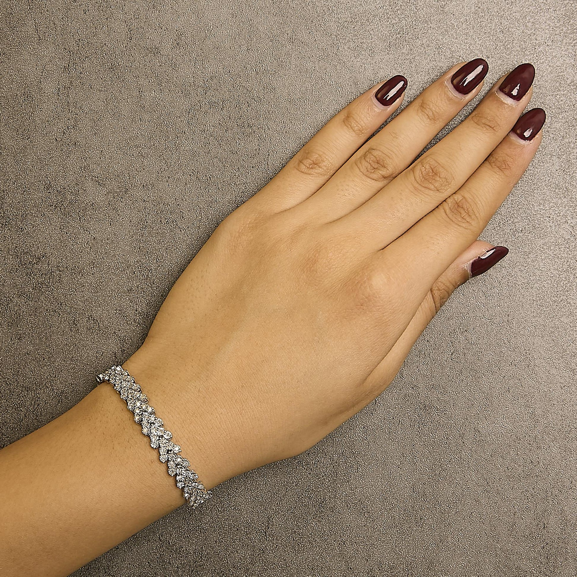 White metal bracelet with round white gemstones in miracle setting, shown on model's wrist from top angle.