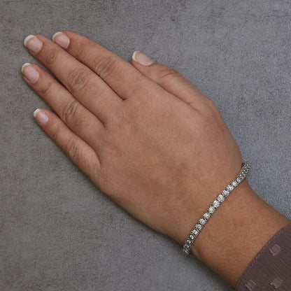 White metal bracelet with round white gemstones, worn on a model's wrist, shot from above at an angle.
