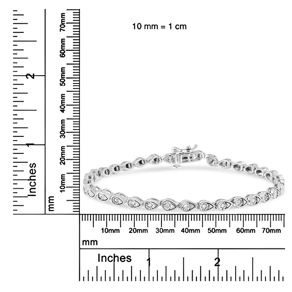 White bracelet with teardrop-shaped settings holding round white gemstones, shown on a ruler for size reference, photographed from a front angle.