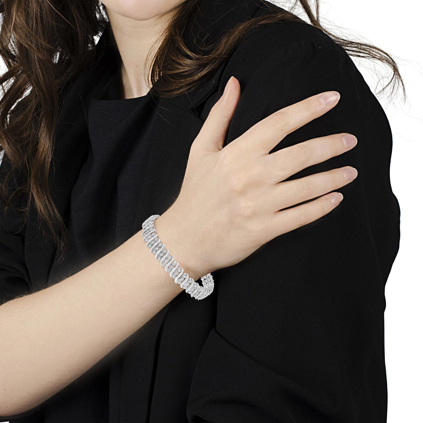 White metal bracelet with round white gemstones in prong settings, worn on a model's wrist, shown from a front angle.