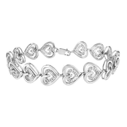 White metal bracelet with linked open heart shapes each set with small round white gemstones, shown in a side angle view.