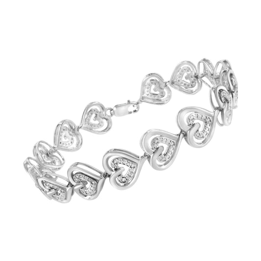 White metal bracelet with linked open heart shapes accented with round white gemstones, shown at a slight angle.