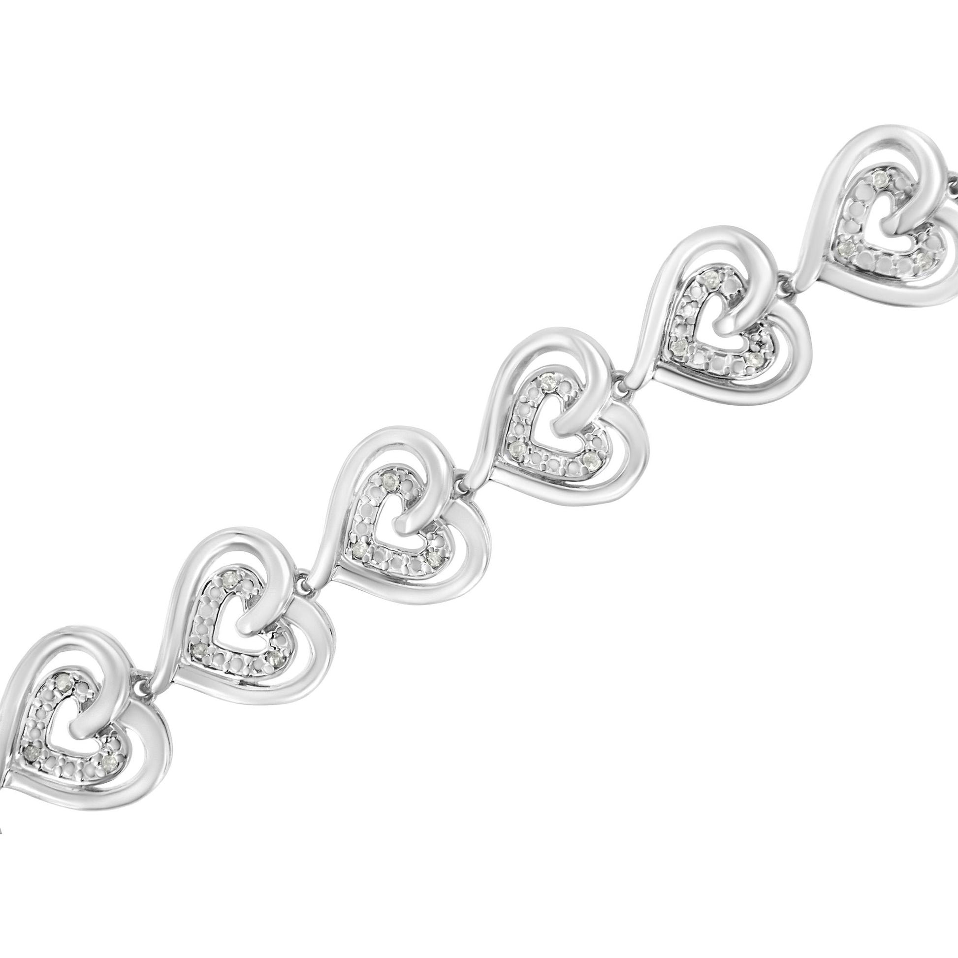 Diagonal close-up of a white metal bracelet featuring linked heart shapes with round white gemstones in prong settings.