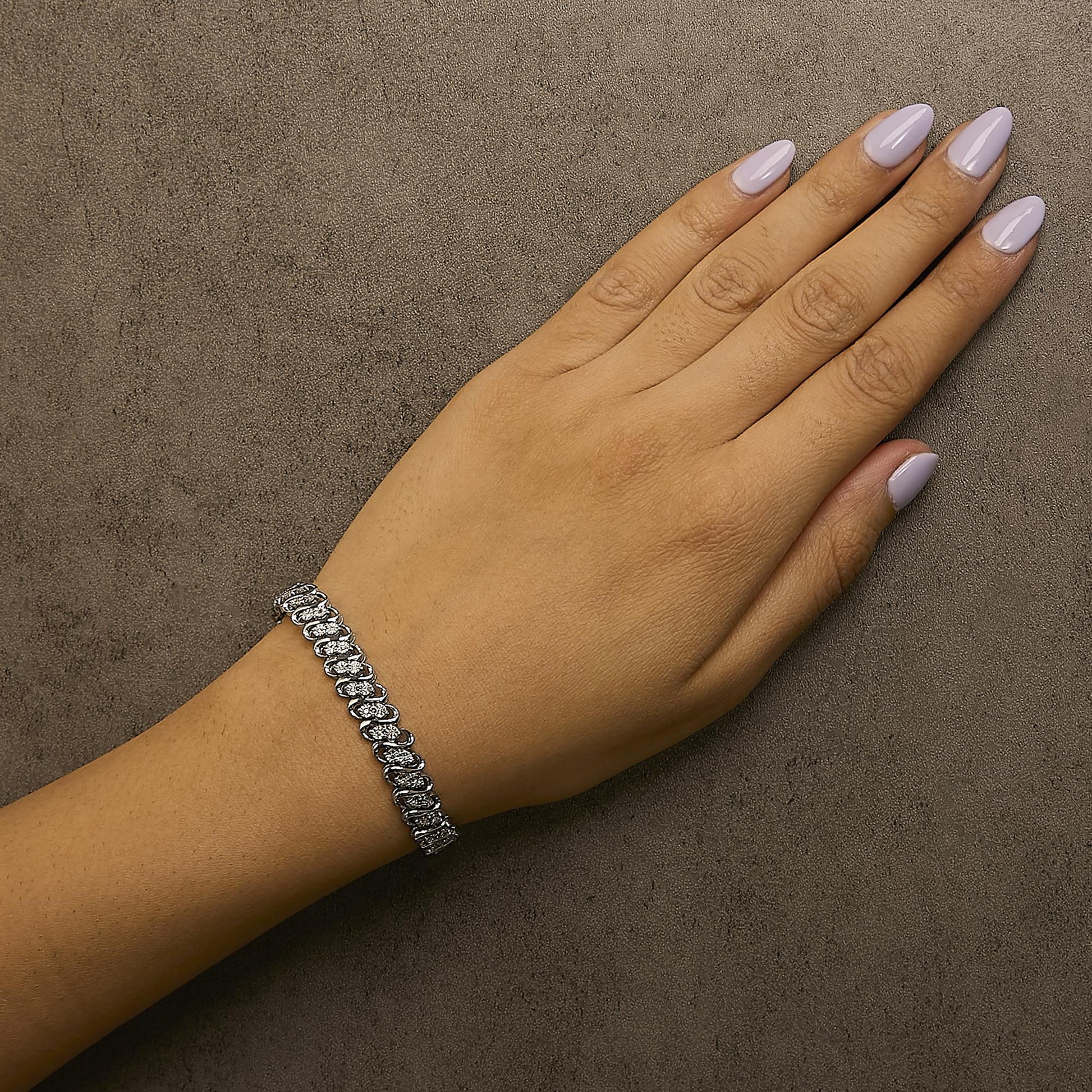 White metal bracelet with round white gemstones in miracle setting, shown on a model's wrist from a side angle.