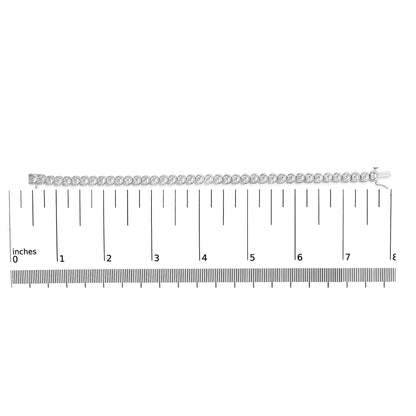 White metal bracelet with round white gemstones in miracle settings, laid flat on a ruler for size reference, shot from above.