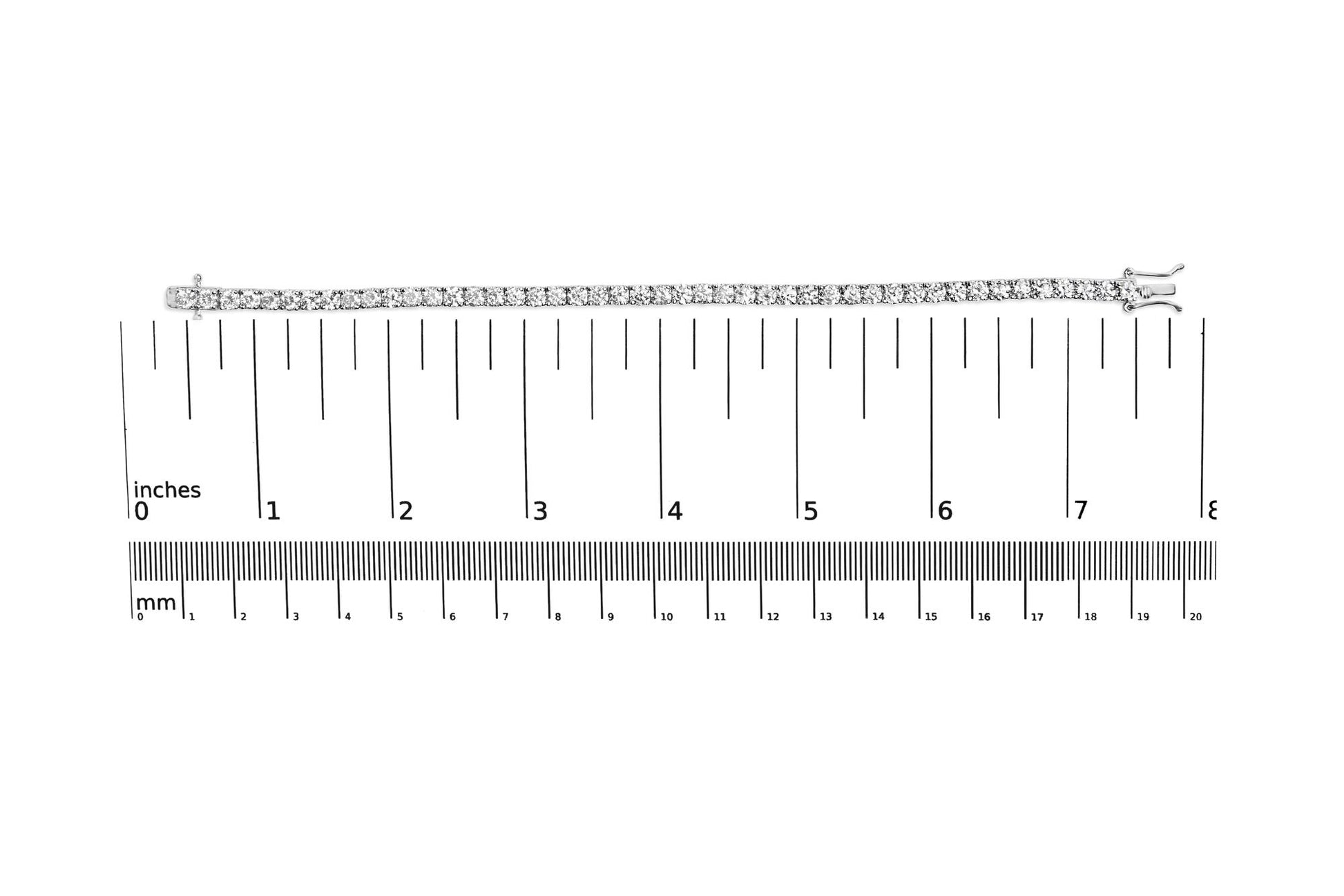 White metal bracelet with round white gemstones in 4-prong settings, laid flat on a ruler and scale for size reference, top-down view.