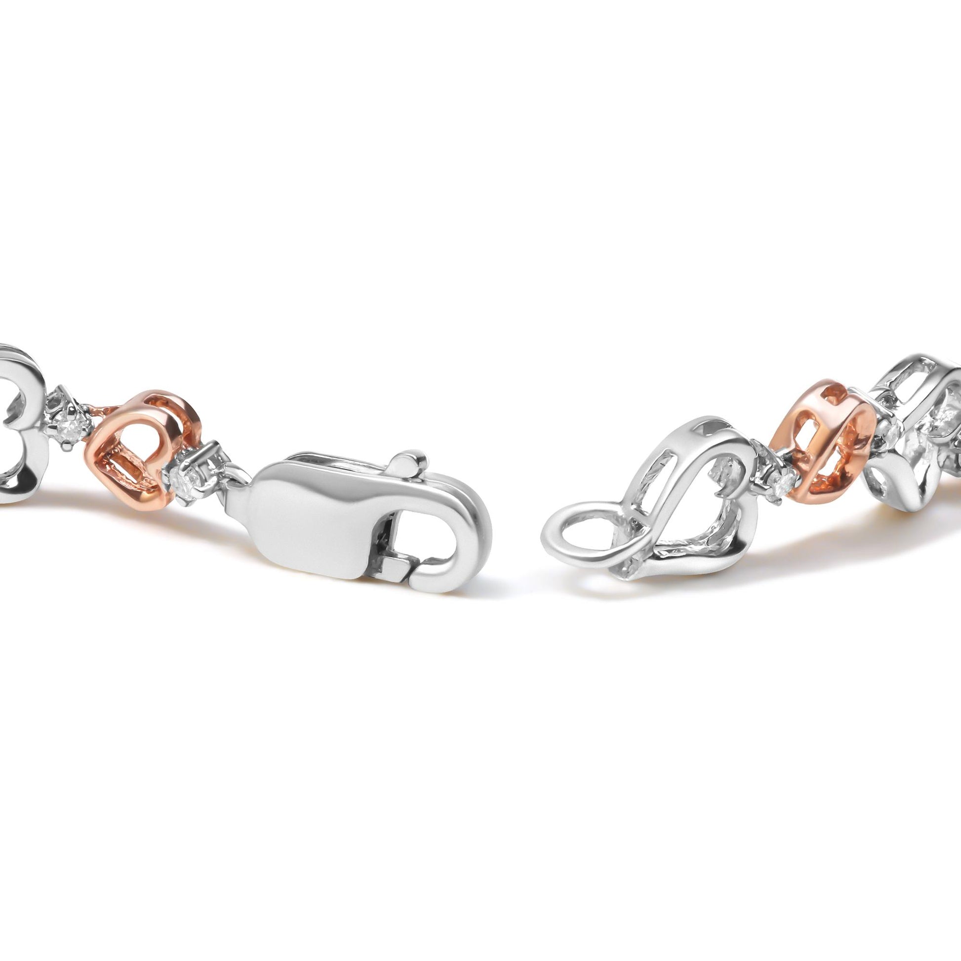 Close-up of a white and rose metal bracelet with heart-shaped links and round white gemstones in prong settings, shown from a side angle.