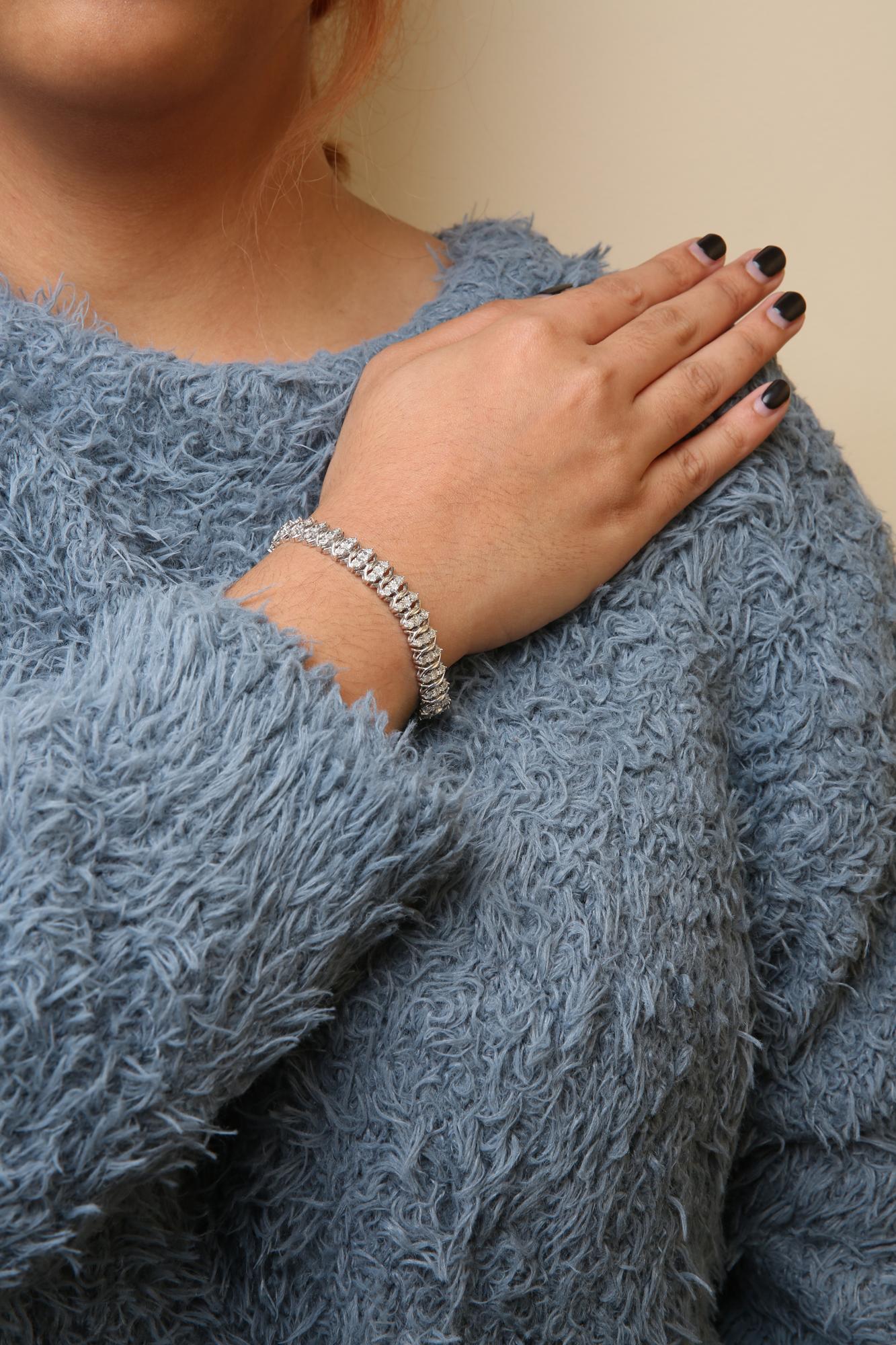 White metal bracelet with round white gemstones in miracle setting, shown on a model's wrist from a side angle.