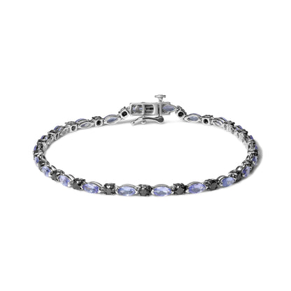 White metal bracelet viewed from above, featuring alternating blue marquise-shaped gemstones and round black gemstones in prong settings.