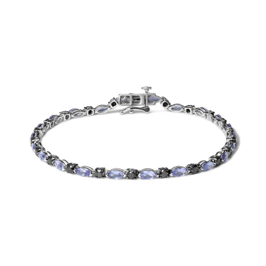 White metal bracelet viewed from above, featuring alternating blue marquise-shaped gemstones and round black gemstones in prong settings.