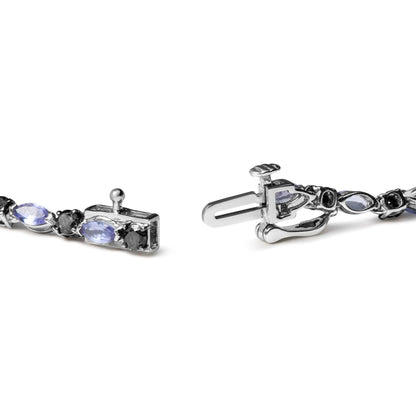 Close-up angled view of a white metal bracelet clasp featuring alternating marquise-shaped blue gemstones and round black gemstones in prong settings.