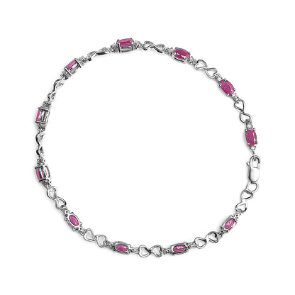 Top-down view of a white metal bracelet featuring alternating oval pink gemstones and heart-shaped links, interspersed with round white gemstones in prong settings.