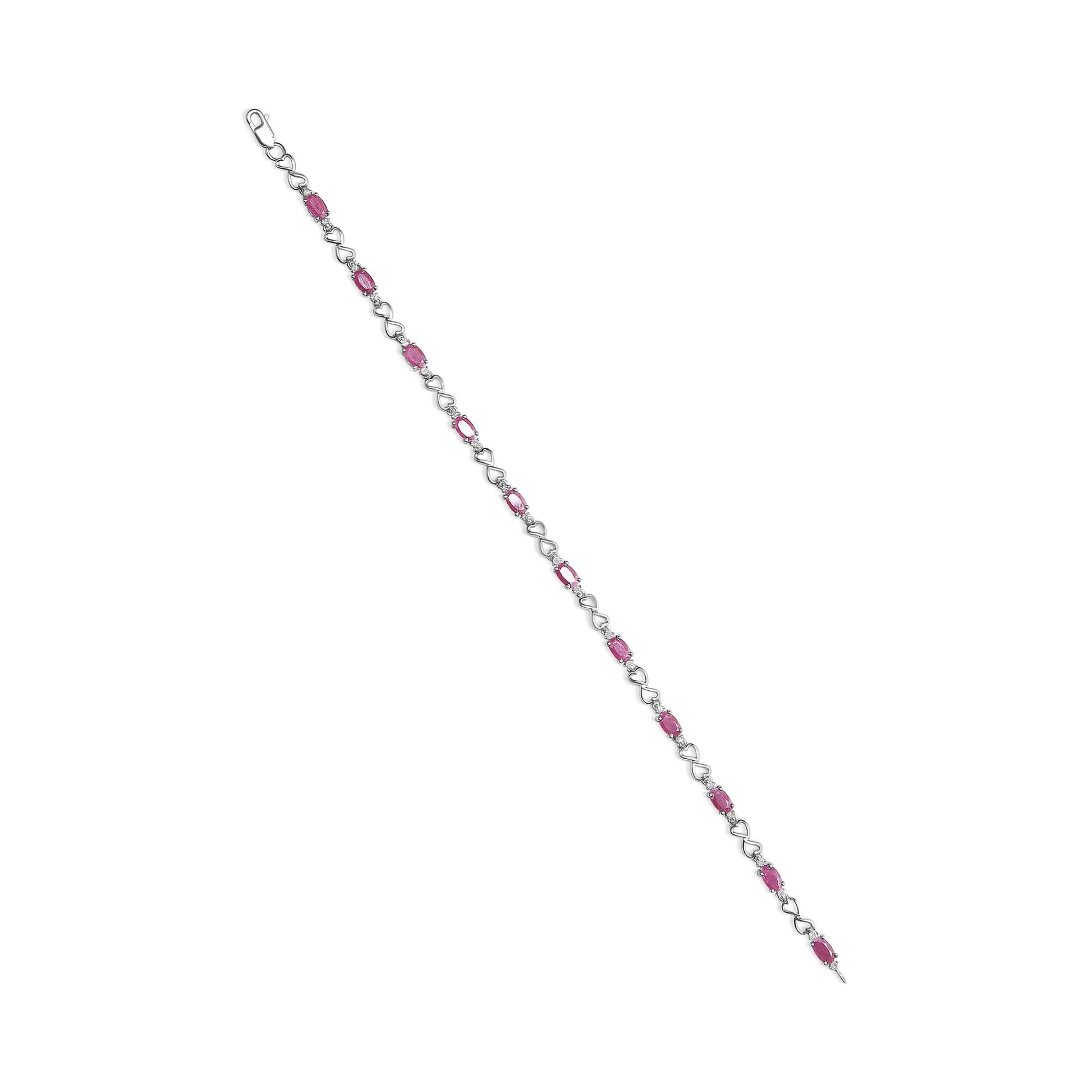Diagonal view of a white metal bracelet featuring evenly spaced oval pink gemstones and small round white gemstones in prong settings, connected by heart-shaped links.