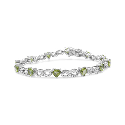 White metal bracelet with alternating heart-shaped green gemstones and infinity symbols set with small white gemstones, shown at a slight angle.