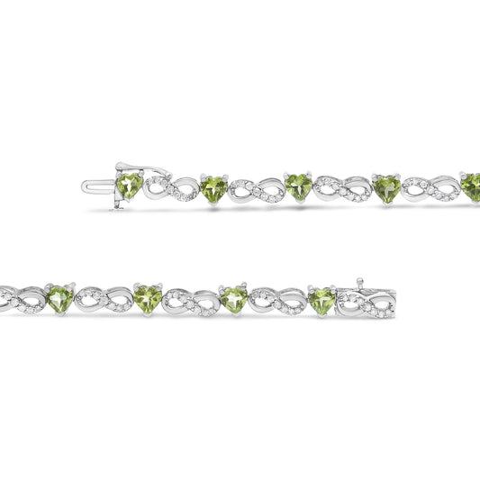 Close-up front view of a white metal bracelet featuring alternating heart-shaped green gemstones and infinity-shaped links set with small round white gemstones.