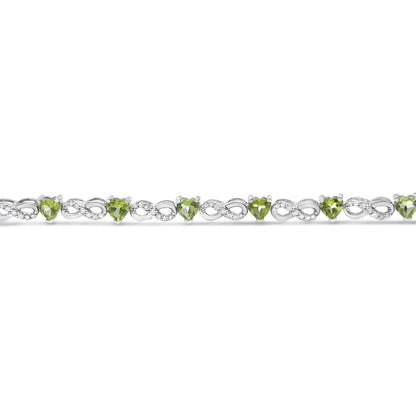 Front angle view of a white bracelet featuring alternating round white gemstones in prong settings and heart-shaped green gemstones in three-prong settings.