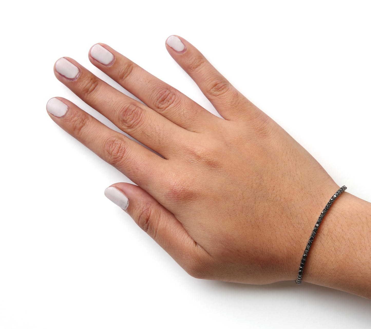 White metal bracelet with round black gemstones in prong setting, shown on a model's wrist from a top-down angle.