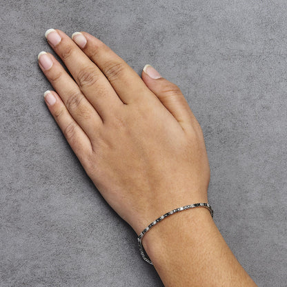 White metal bracelet with alternating black and white round gemstones in prong settings, shown on a model's wrist from a top-down angle.
