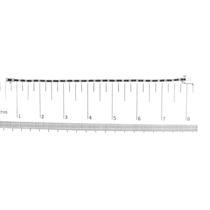 White metal bracelet with alternating black and white round gemstones in prong settings, shown flat on a ruler for size reference, top-down angle.