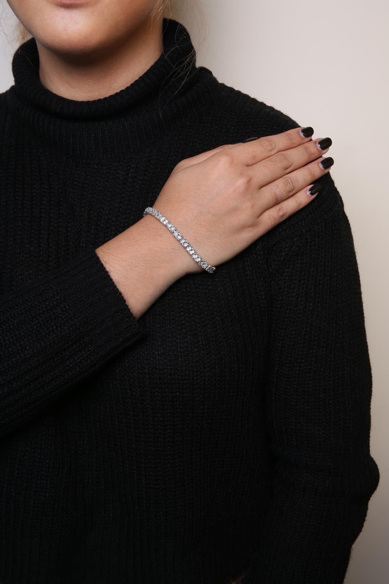 White metal bracelet with round white gemstones in miracle setting, worn on a model shown from the front at an angle.