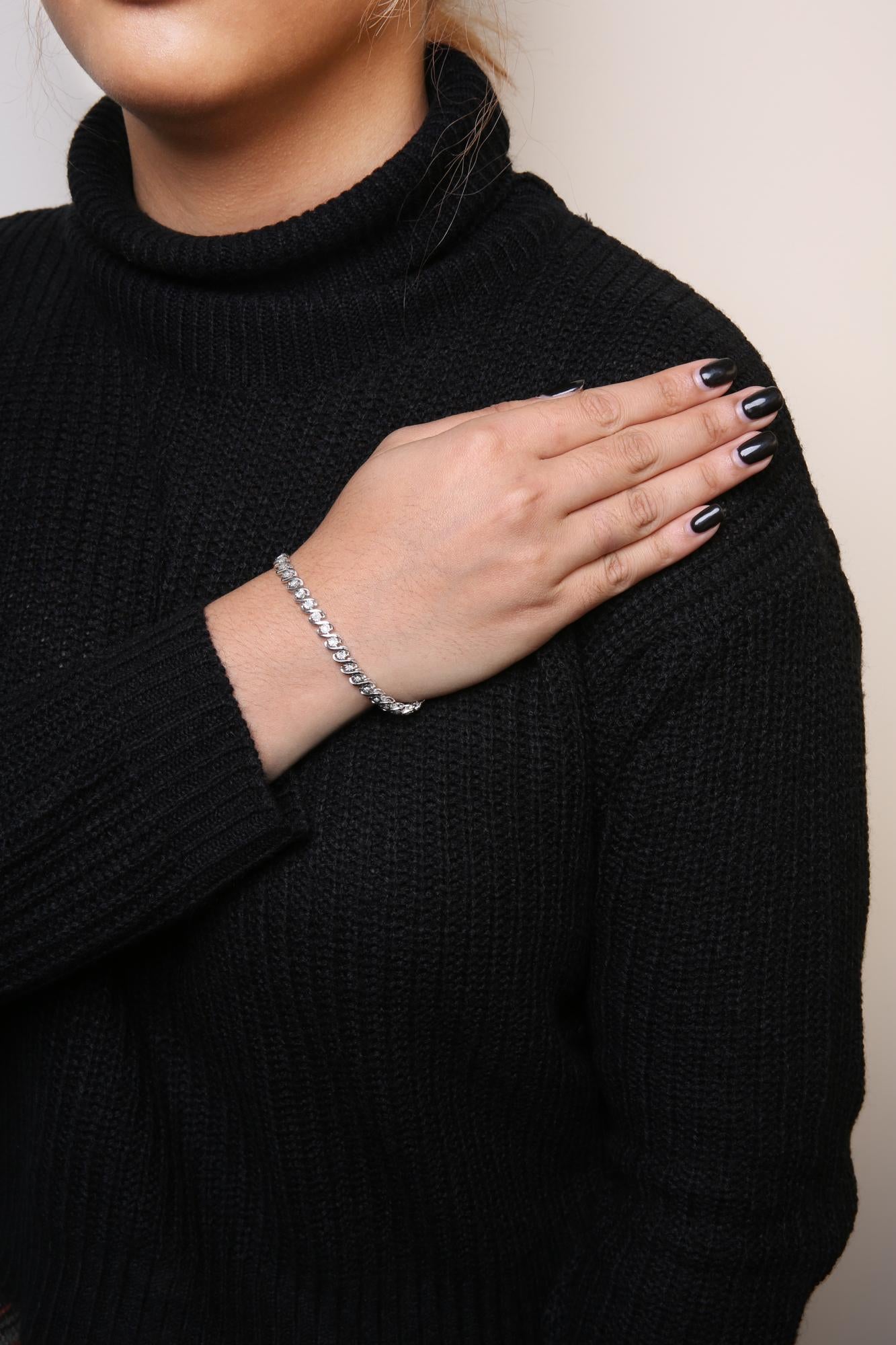 White metal bracelet with round white gemstones in miracle setting, worn on model's wrist, front angle.