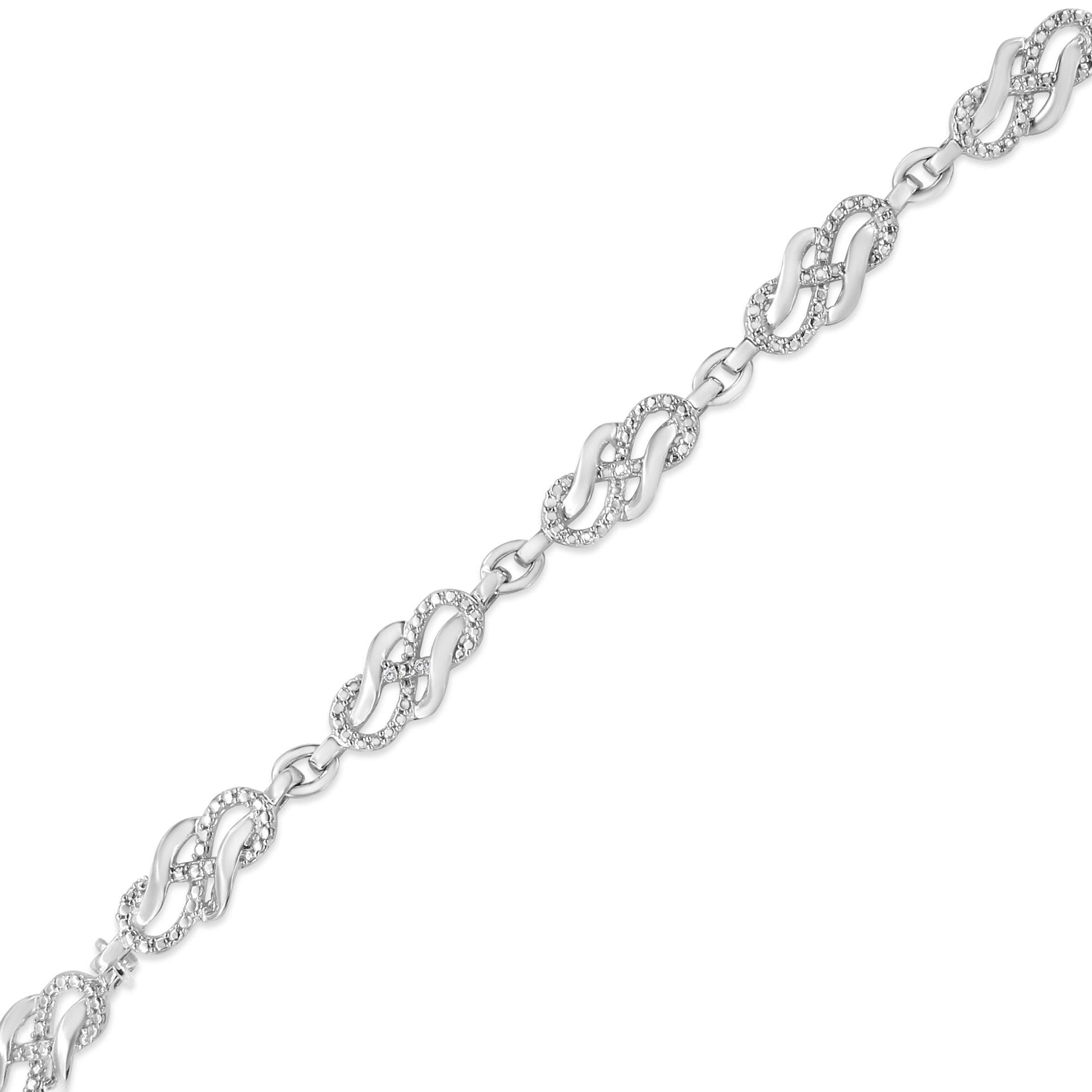 Diagonal top-down view of a white metal bracelet featuring linked oval shapes with small round white gemstones in prong settings.