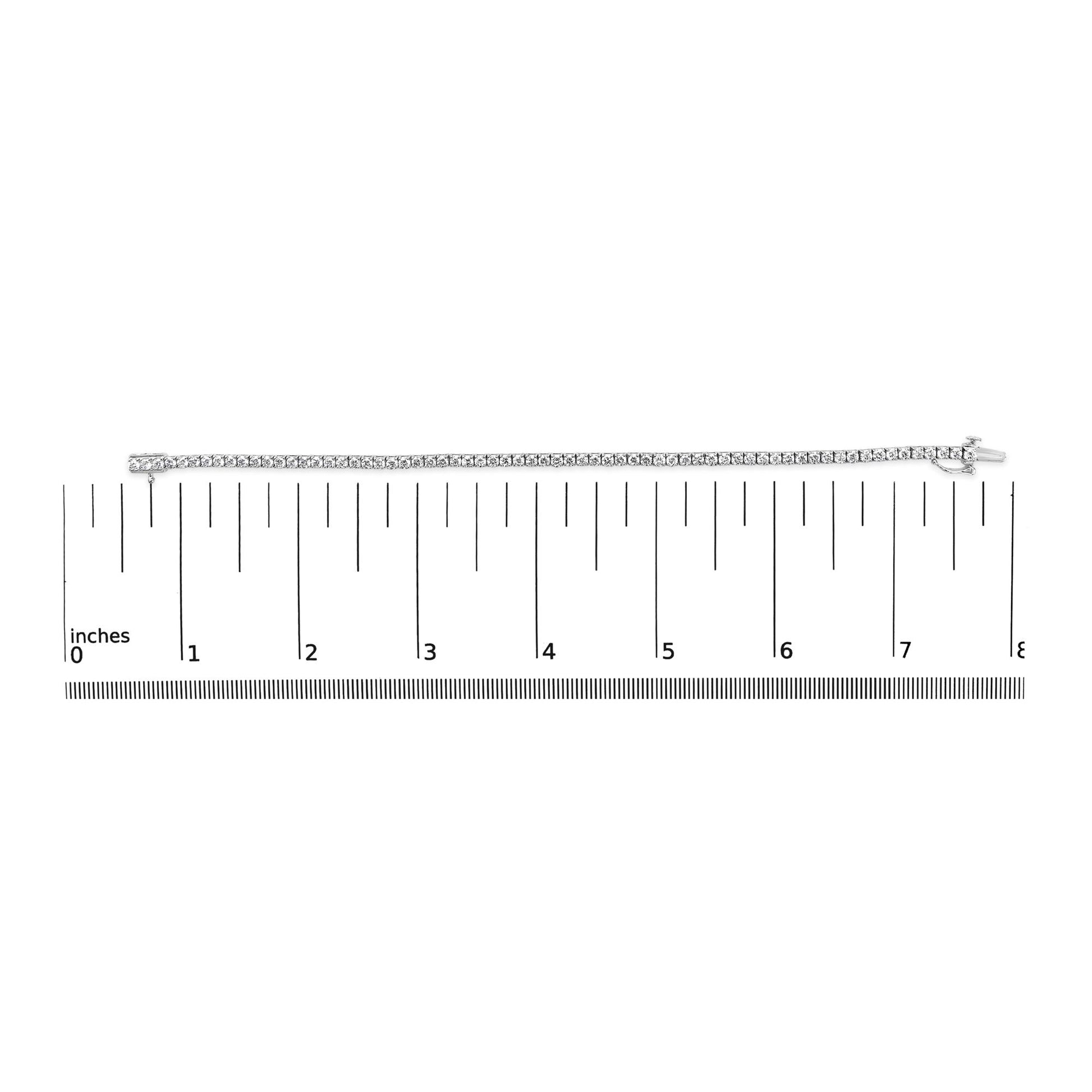 White metal bracelet with round white gemstones in 4-prong settings, displayed horizontally on a ruler for size reference, top-down view.