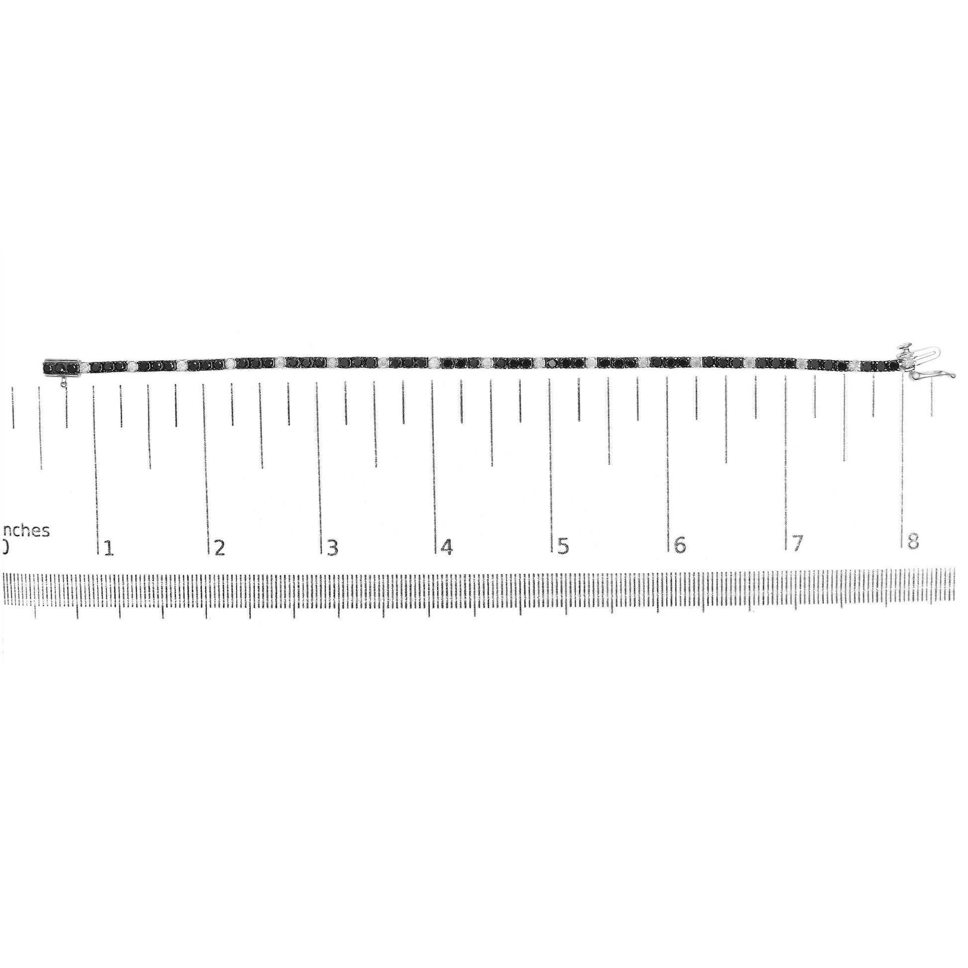 White metal bracelet with alternating round black and white gemstones in 4-prong settings, displayed horizontally on a ruler for size reference, shot from above.