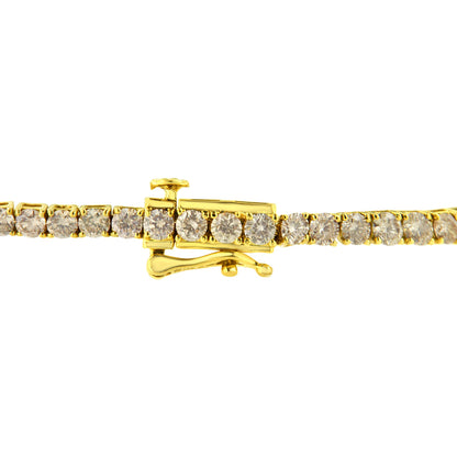 Close-up side view of a yellow metal bracelet with round brownish gemstones in prong settings and a clasp.