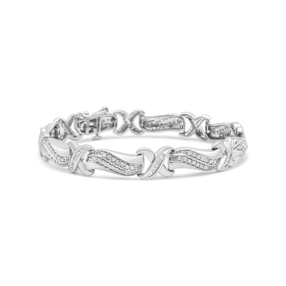 White metal bracelet with crisscross and wave design featuring round and baguette shaped white gemstones, shown from front angle.