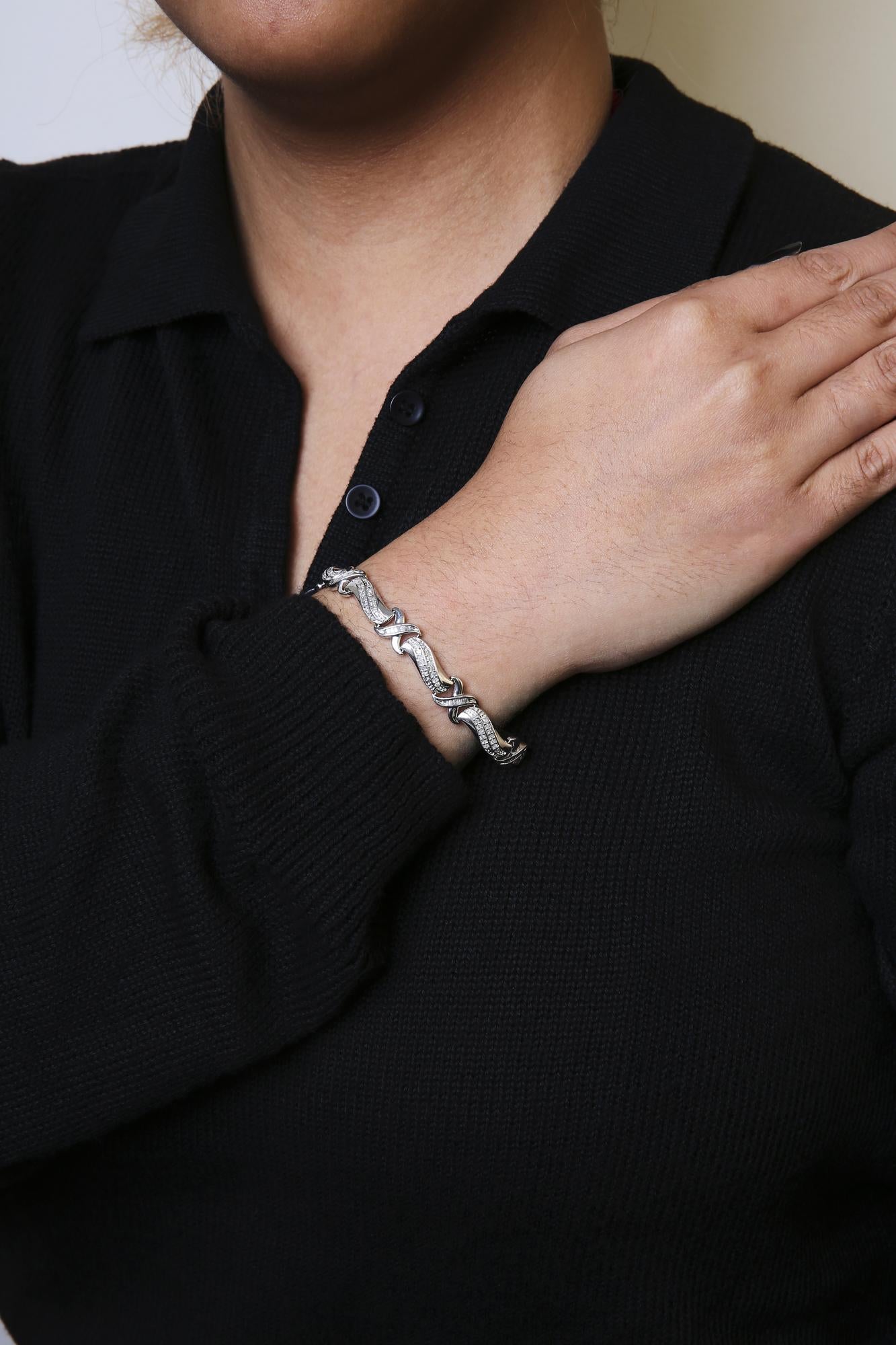 Close-up front angle of a white bracelet with round prong-set white gemstones and baguette channel-set white gemstones, worn on a model's wrist.