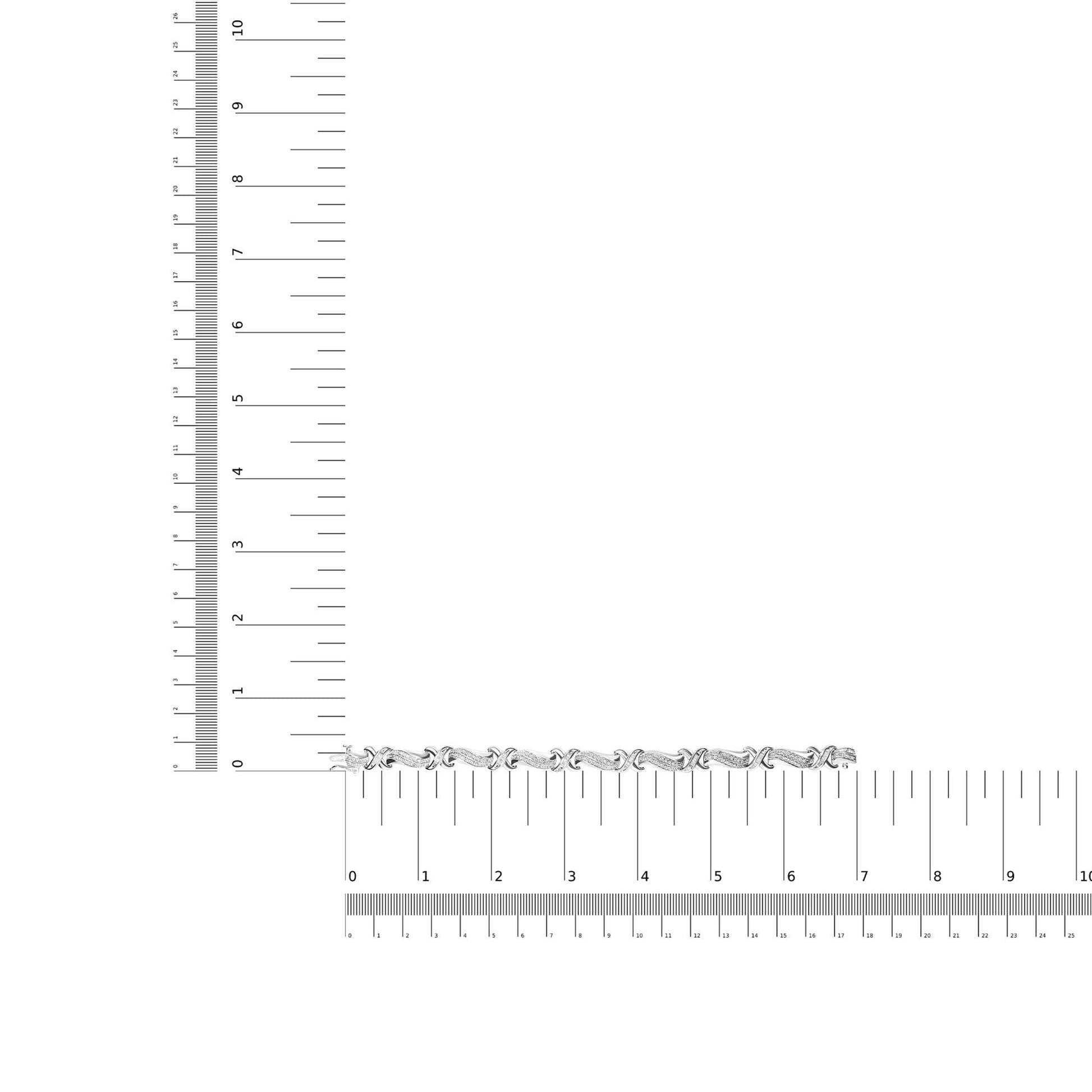 White metal bracelet with alternating linked sections featuring round and baguette shaped white gemstones in prong and channel settings, displayed flat on rulers for size reference, top-down view.