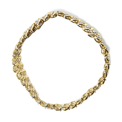 Yellow metal bracelet with alternating openwork links set with white round gemstones, shown flat from above.
