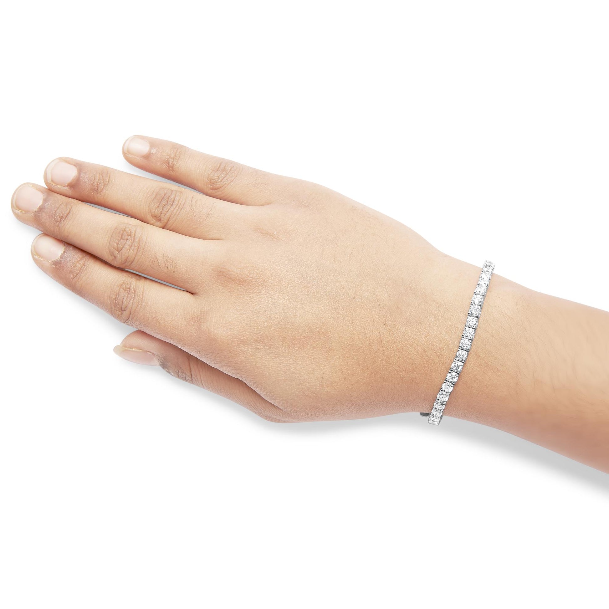 White metal bracelet with round white gemstones in four-prong settings, worn on wrist, side angle.