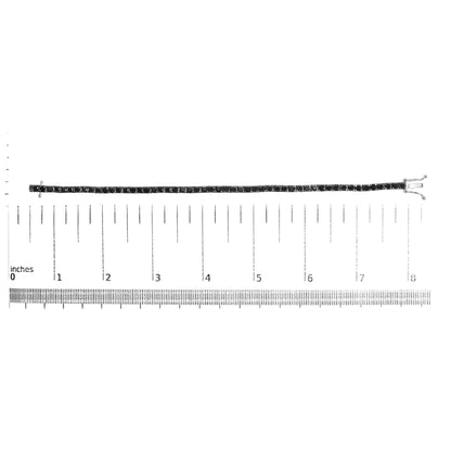 White metal bracelet with black round gemstones in prong settings, laid flat on a ruler for size reference, shot from above.