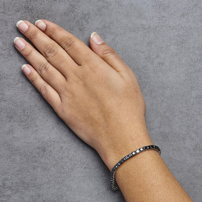 White metal bracelet with round black gemstones in prong settings, shown on a model's wrist from a top angle.