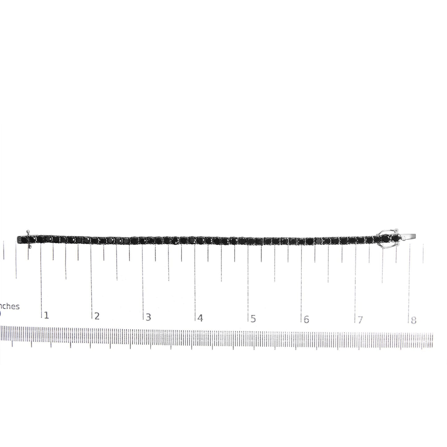 White metal bracelet with round black gemstones in prong settings, displayed flat on a ruler for size reference, shot from above.