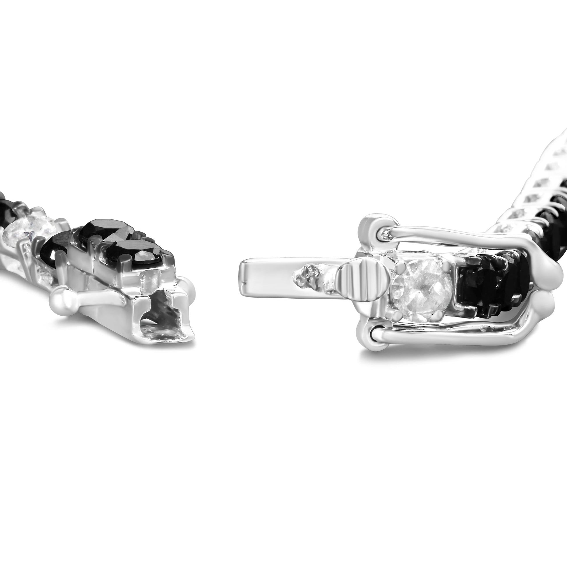 Close-up side angle of a white metal bracelet with round black and white gemstones in 4-prong settings, showing the clasp open.