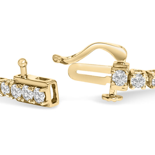 Close-up angled view of a yellow metal bracelet clasp featuring round white gemstones in four-prong settings.