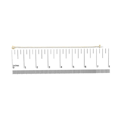 Top view of a yellow metal bracelet with round white gemstones in prong settings, shown on a scale.